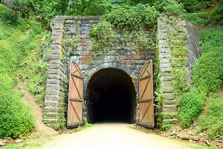 树林中一条自行车道上的古老石隧道入口从旧铁路轨迹图片