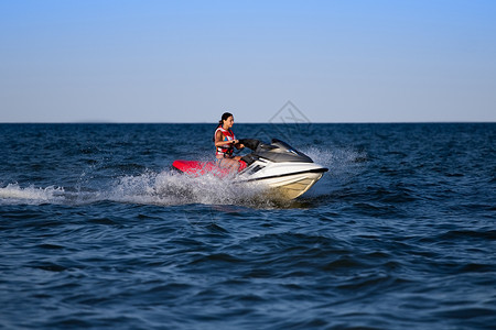穿着救生衣的年轻黑发女郎骑着摩托艇背景图片