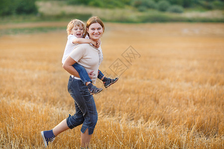年轻母亲和小儿子在日落的夏天在黄图片