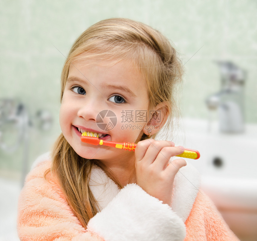 微笑的小女孩在浴缸里刷牙图片