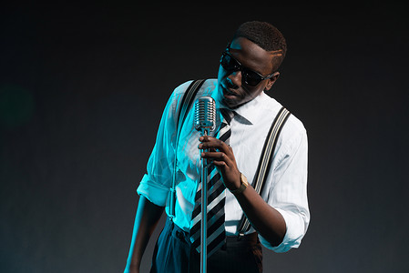 带麦克风的非洲爵士歌手穿着衬衫领带和墨镜图片