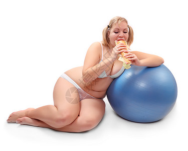 超重女人坐在健身球上吃大三明治的有趣照片图片