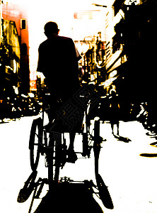 在黄昏的胡志明市中心一个骑着三轮车的孤单男人的背后呈现出图片