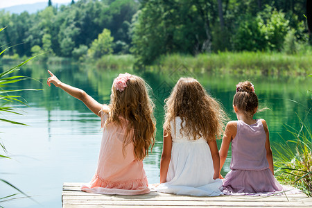 三个小孩坐在湖边的码图片