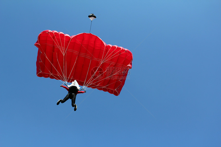 蓝天上带着红色降落伞的跳伞者图片