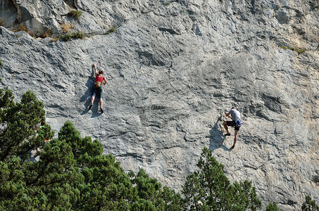 一个男人和一个女人爬上自然岩图片