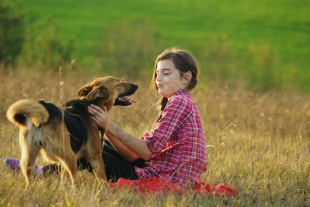 十几岁的女孩在田野里和她的狗玩耍图片