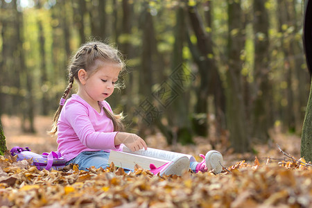 小女孩在秋天的森林里看书图片
