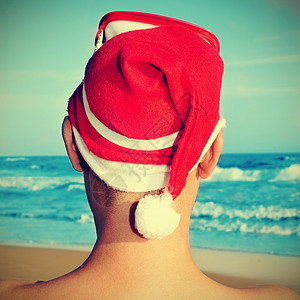照片显示海滩上有人戴圣诞老人帽子图片
