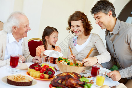快乐家庭在感恩节晚宴时坐在节日餐桌边的喜图片