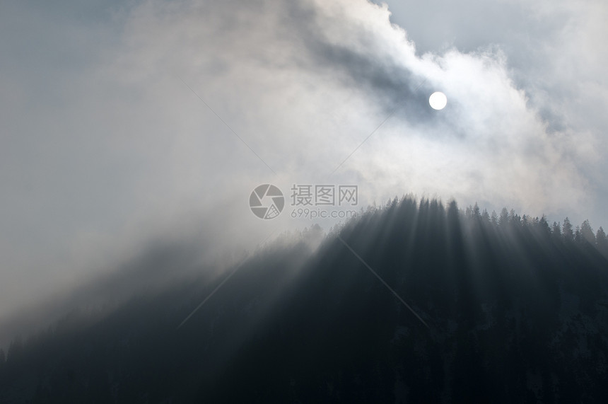 神秘的阳光照射在山上的雾林图片