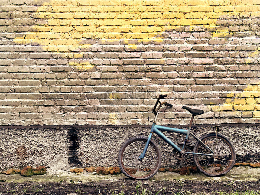 靠在砖墙上的生锈的老式自行车图片