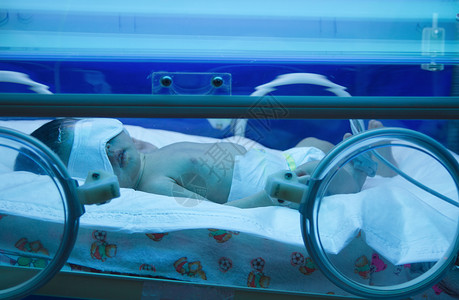 保育箱紫外线灯下的新生婴儿背景图片