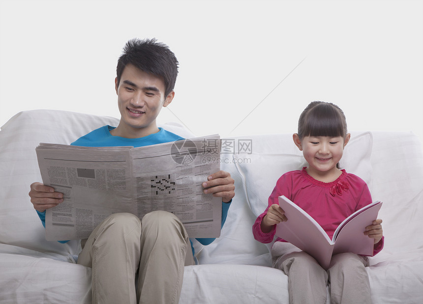 父亲和女儿坐在沙发上单独阅读图片