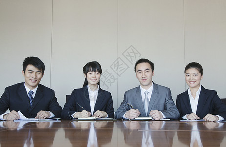 四位年轻人坐在一排在会议桌边的图片