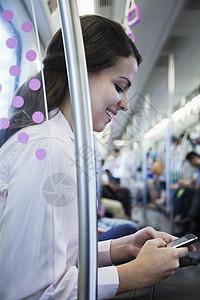 坐在地铁上并使用手机的女图片
