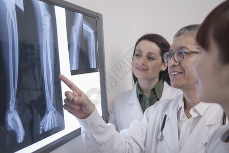 三名笑着的医生在看X光片的人骨图片