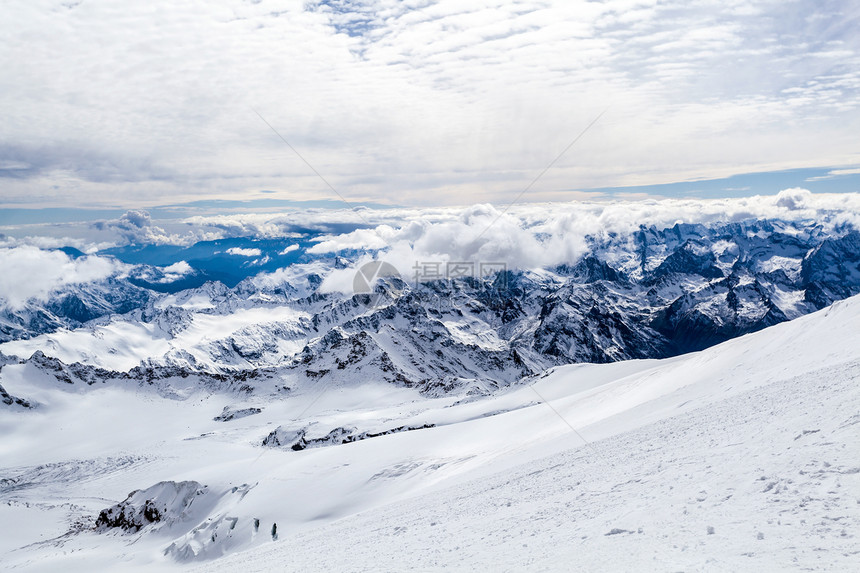 俄罗斯和格鲁吉亚的高加索山脉冬季山地景观从厄尔布鲁士山5642m的斜坡上查看大量的白雪在落基山脊上蓝天晴朗的图片