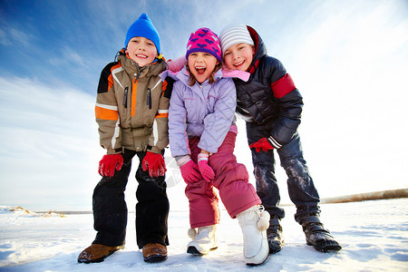 穿着冬装的快乐孩子一边看着相机一边在外面度图片