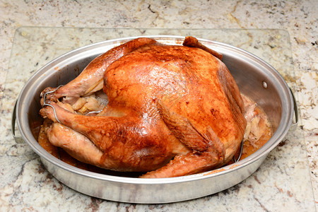 在厨房柜台的烤锅里关闭一个煮熟的感恩节火鸡火鸡刚从烤箱出来图片