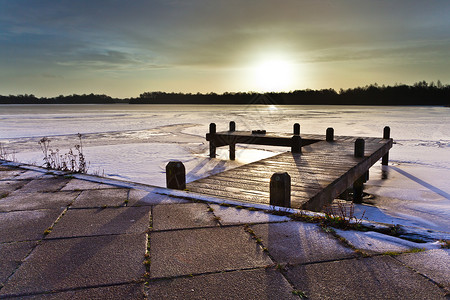 冰雪结冰的冬季湖上的码头上的琥珀色日出图片