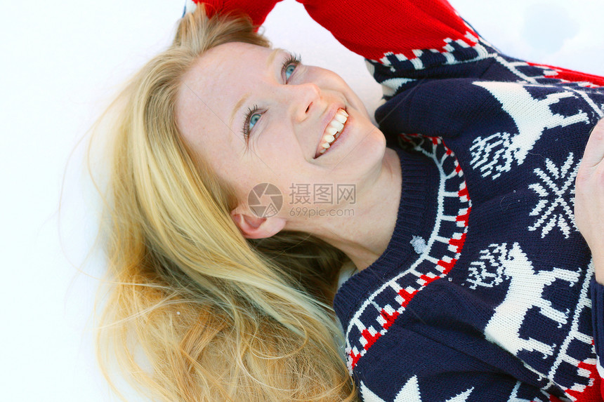 身穿圣诞滑雪毛衣的30岁有魅力笑容的女人躺在外面的冬雪中图片