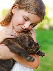 可爱的小女孩拥抱她的小狗日落友图片
