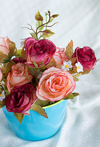 桌布背景上蓝色杯子中的玫瑰花图片