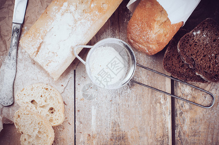 白色法式长棍面包和新鲜质朴的全麦黑面包切片和木板上的面粉面包图片