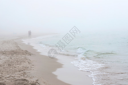 海边有雾的天气波兰莱巴的波罗的海滩沿着海岸线散步的夫妇波兰莱巴的图片