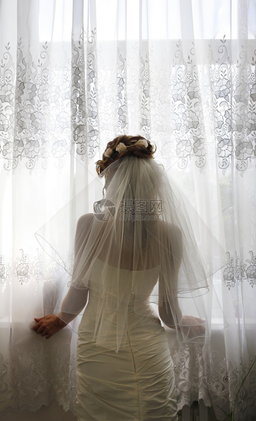 美丽的新娘为婚礼做准备在窗子背图片