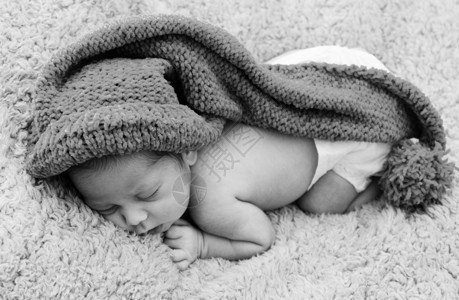 新生婴儿戴着蓝帽子躺着睡觉a图片