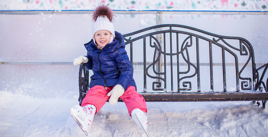 小女孩坐在溜冰场的长凳上图片