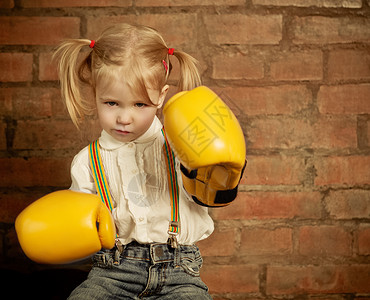 女孩身上戴着黄色拳击手套在砖墙背景上图片