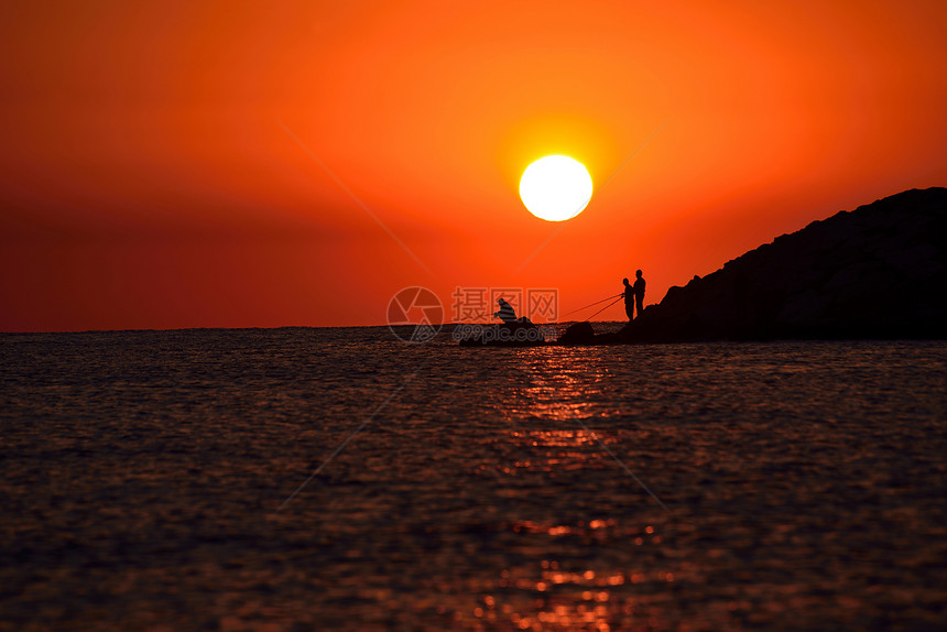 日出时拿着钓鱼竿入海的人剪影图片