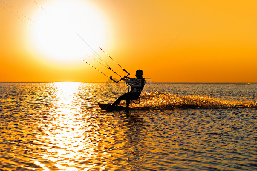 风筝冲浪者在日落时航行的剪影图片
