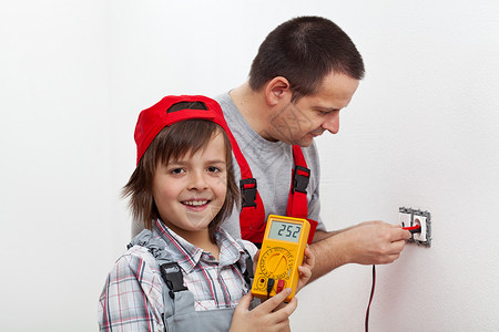 快乐的男孩帮助父亲安装电墙固定装置图片