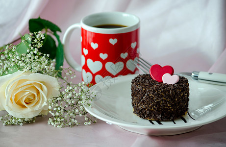 一杯咖啡一朵白玫瑰和一块巧克力蛋糕背景图片