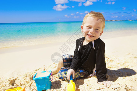 在沙滩上玩沙子的小男孩图片