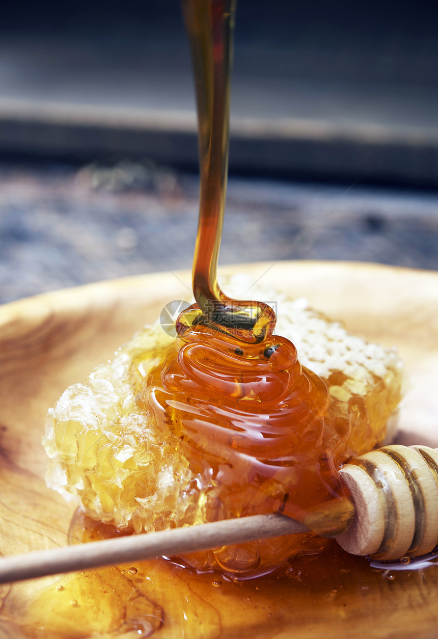 美味的蜂蜜蜂蜜迪珀和蜜蜂窝在木板上图片