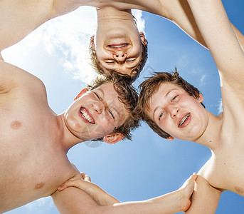 快乐的男孩们在蓝天的圆圈中站在一起图片