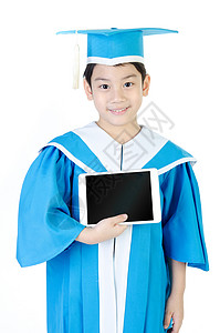 亚洲儿童与平板电脑恭喜幼儿园毕业制服在白种背景上校对图片