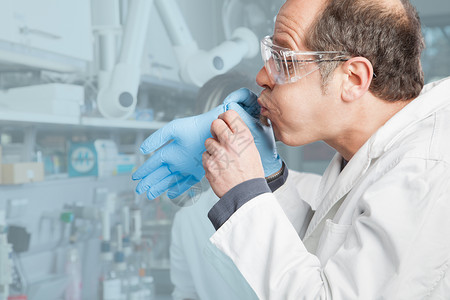 一位化学家在穿衣服前给他的手套充气图片