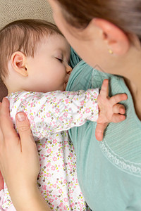 关闭年轻母亲在放松气氛中在家里喂婴儿的母乳图片