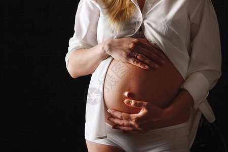 一名孕妇用双手抚摸她的腹部在图片