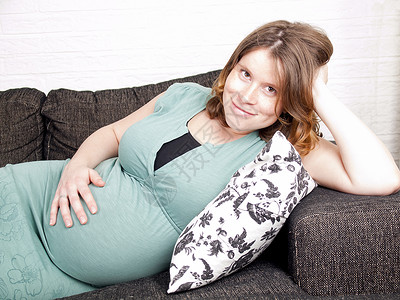怀孕的年轻孕妇在沙发上躺着抱着肚图片