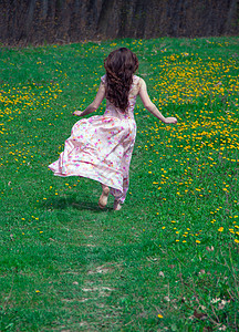 穿粉红裙子的女孩跑在绿草周图片