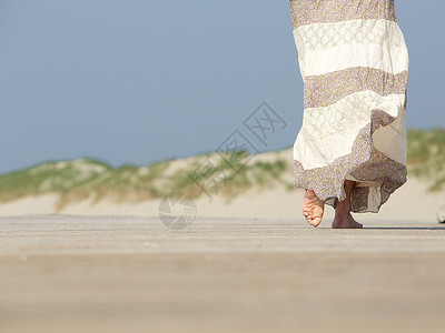 在海滩上走远的赤脚妇女近距图片