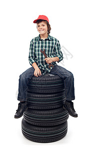 坐在新的车胎轮上拿着扳手的年轻机械工男图片