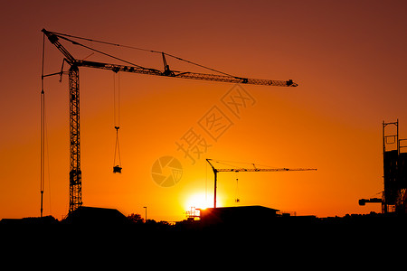 建筑工地的起重机在日落的双影脚架上图片